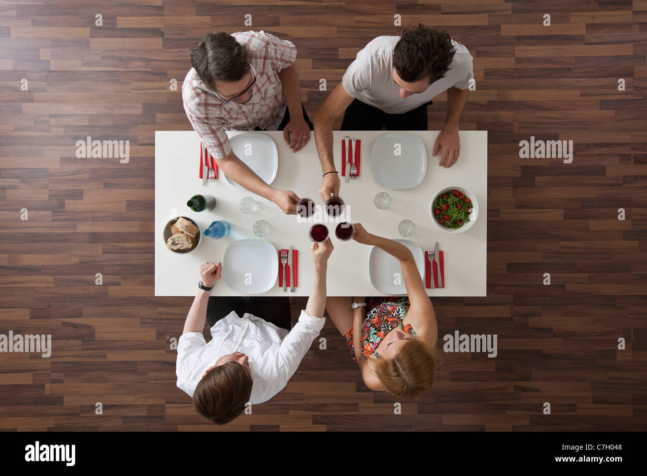 Four friends toasting at a dinner party, overhead view Stock Photo