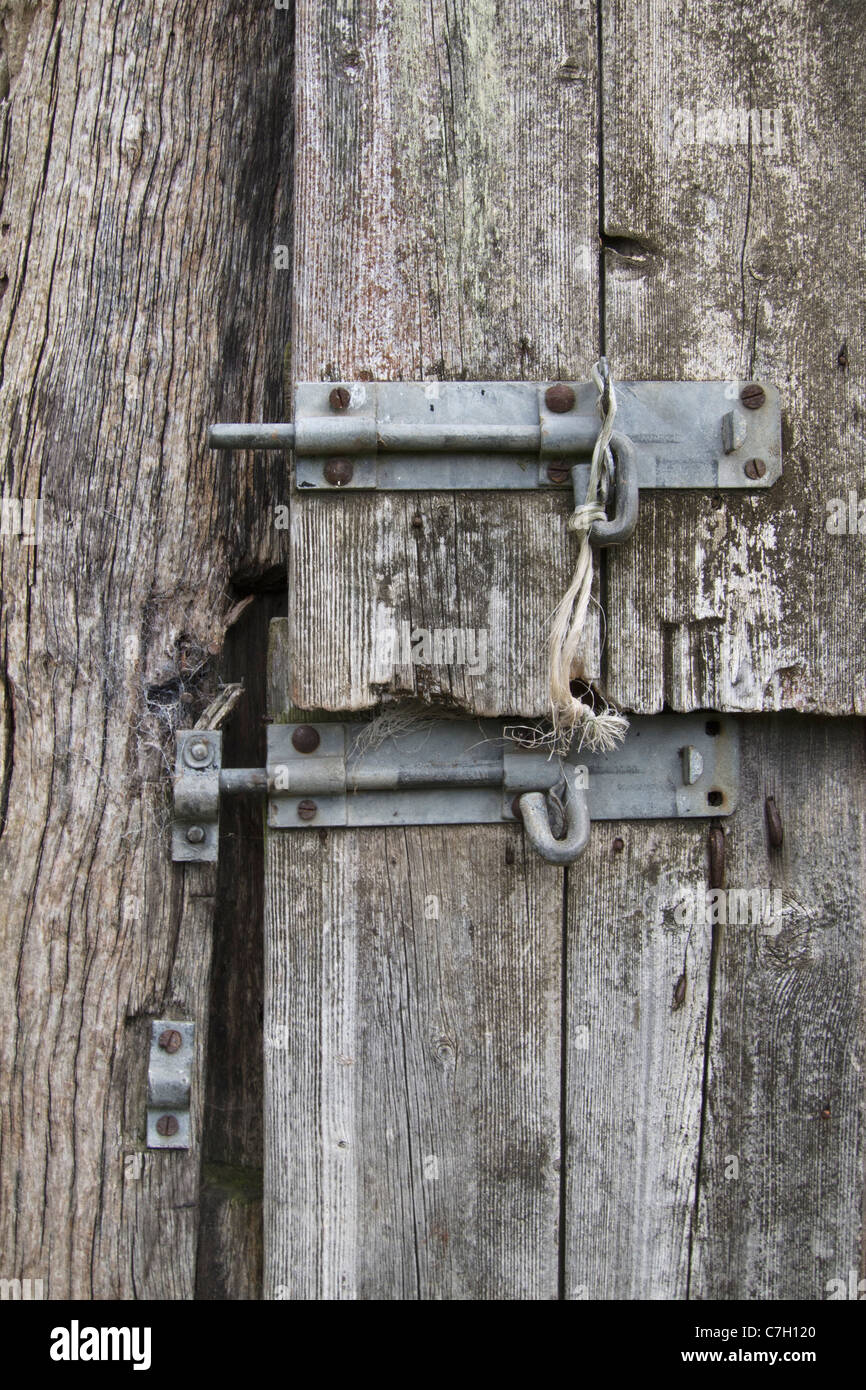 Two slide latches on a warped wooden door Stock Photo