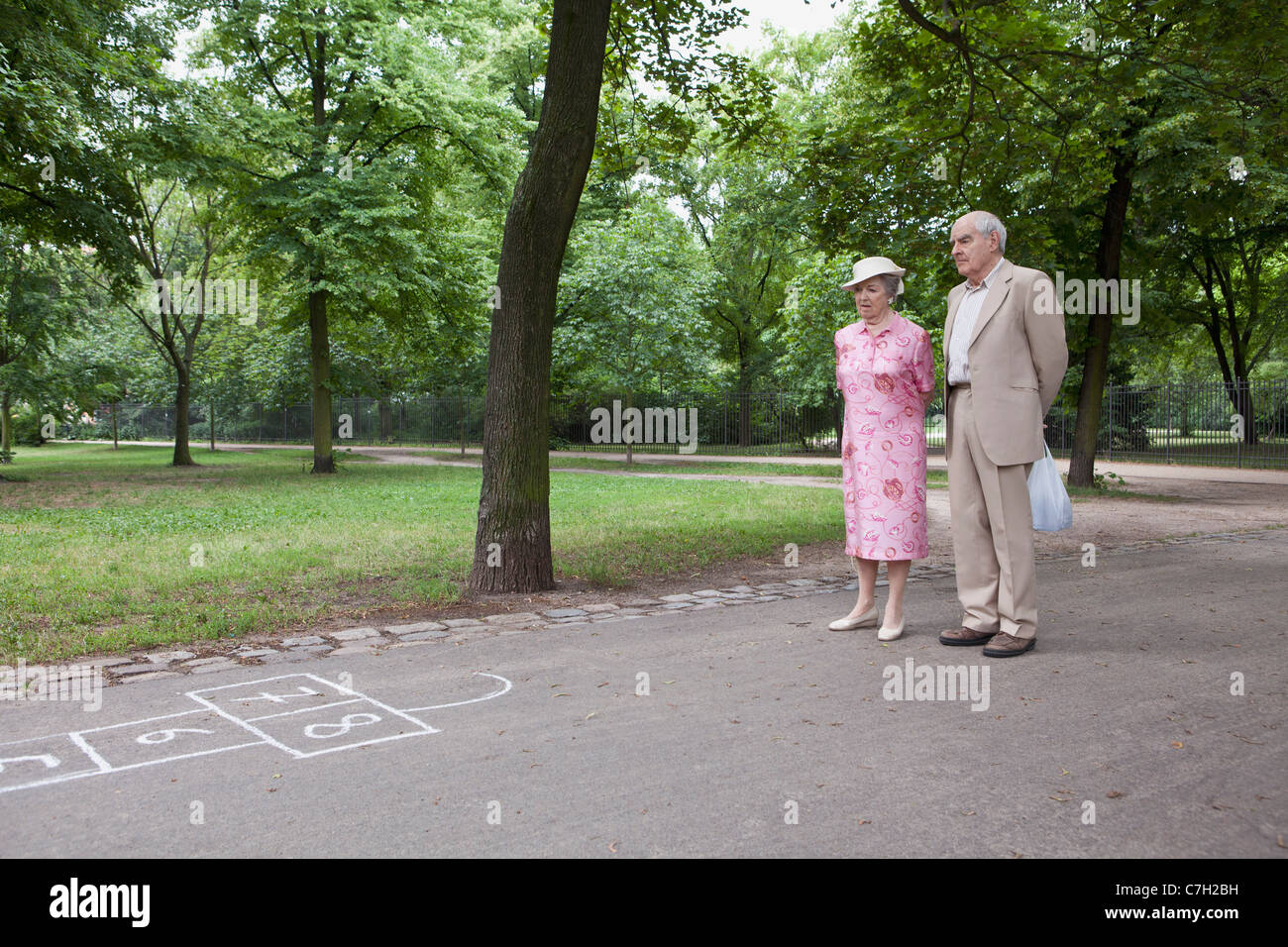 Senior couple contemplate hopscotch in the park Stock Photo