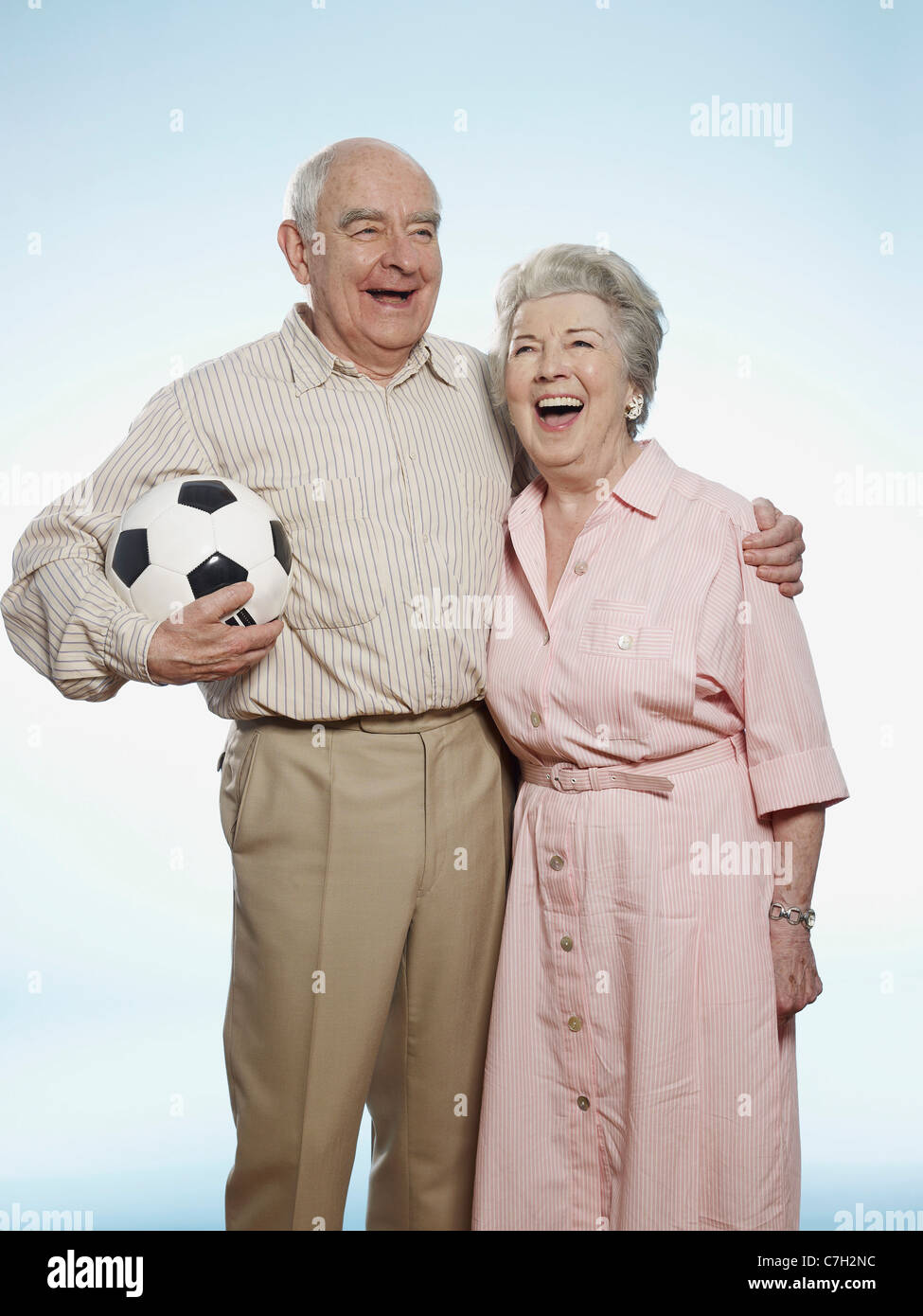 Senior couple laughing as man holds football Stock Photo