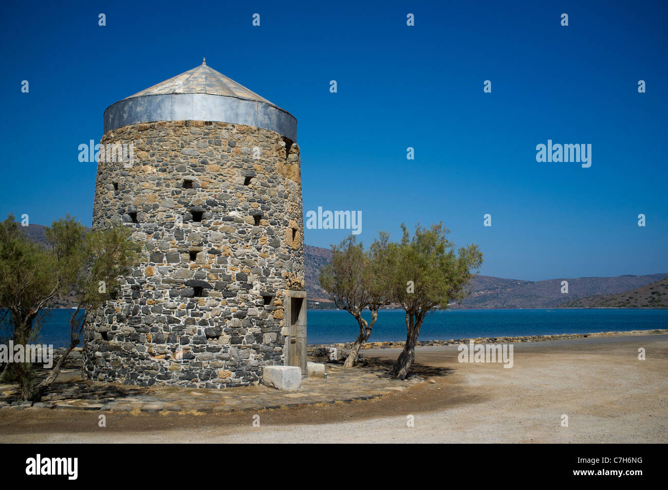 A disused windmill surrounded with olive trees on the Spinalonga peninsular near the resort of Elounda on Crete Stock Photo