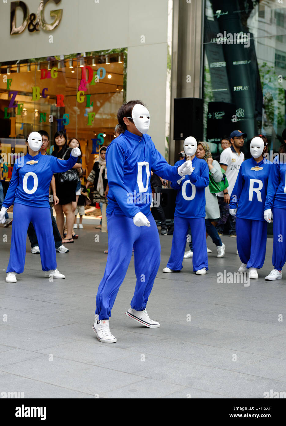 Dance troupe in blue track suits and white masks on Orchard Road, Singapore Stock Photo