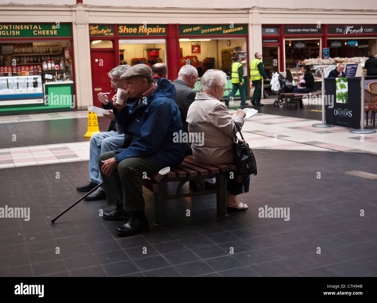 Group of older people sitting on bench in shopping centre at Grainger market Newcastle Stock Photo