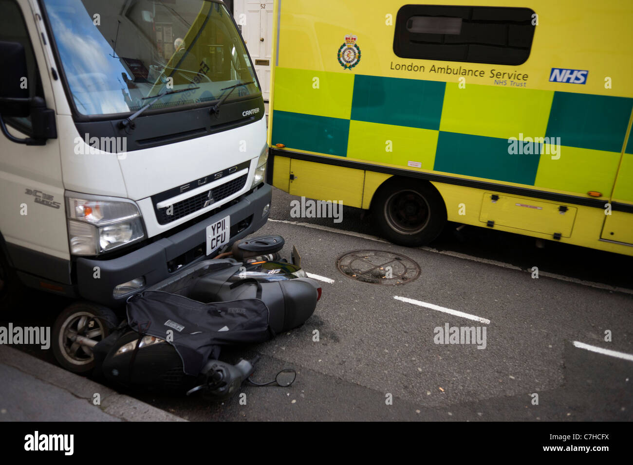A crushed scooter and a passing NHS ambulance in London's West End. Stock Photo