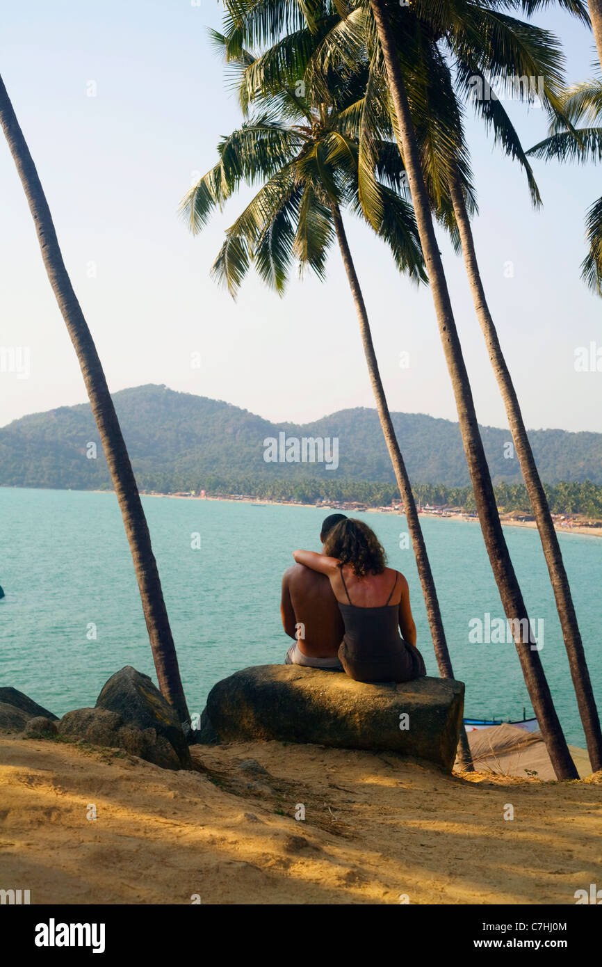 A man and woman sit looking out over a tropical ocean Stock Photo
