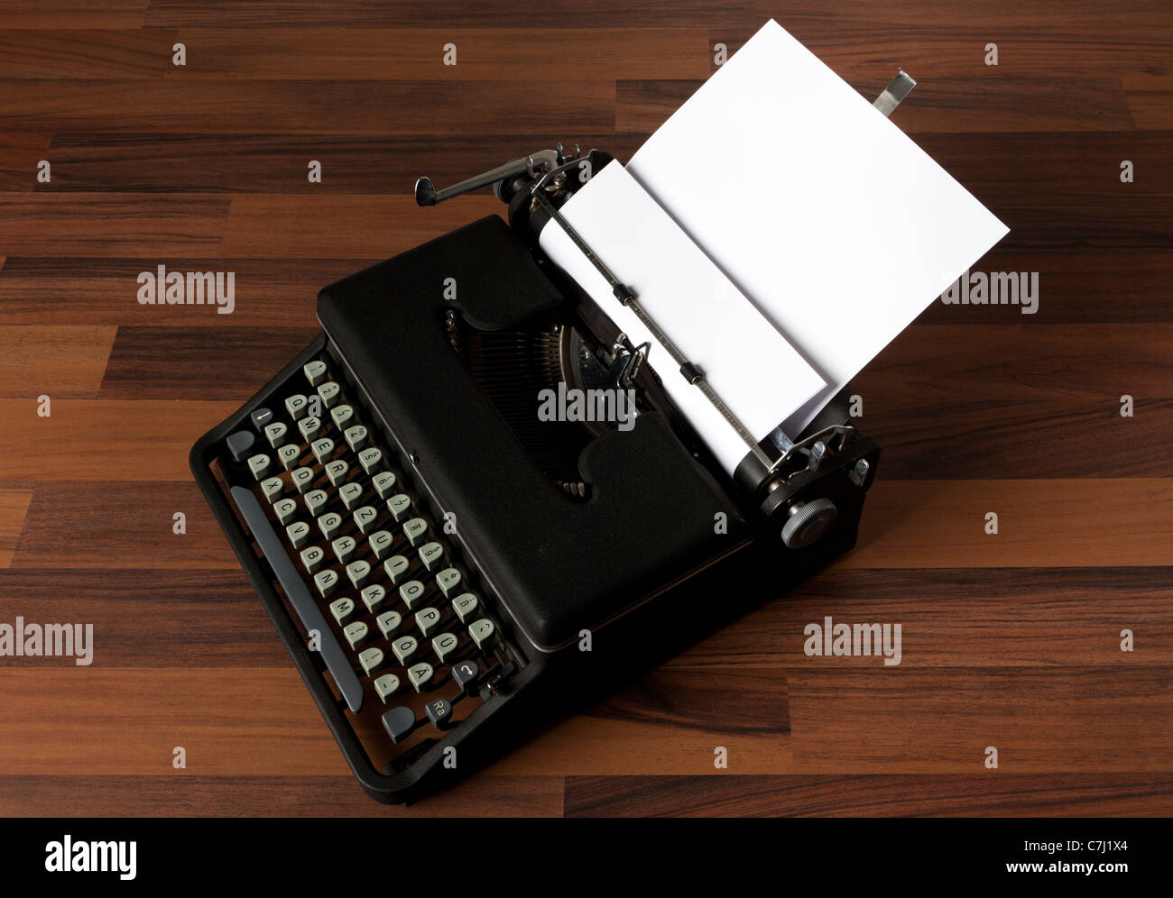 old portable typewriter with blank paper on the floor Stock Photo