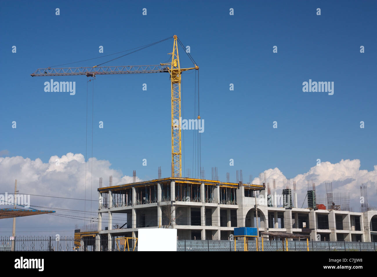 Yellow construction crane, an unfinished concrete house on the skyline Stock Photo