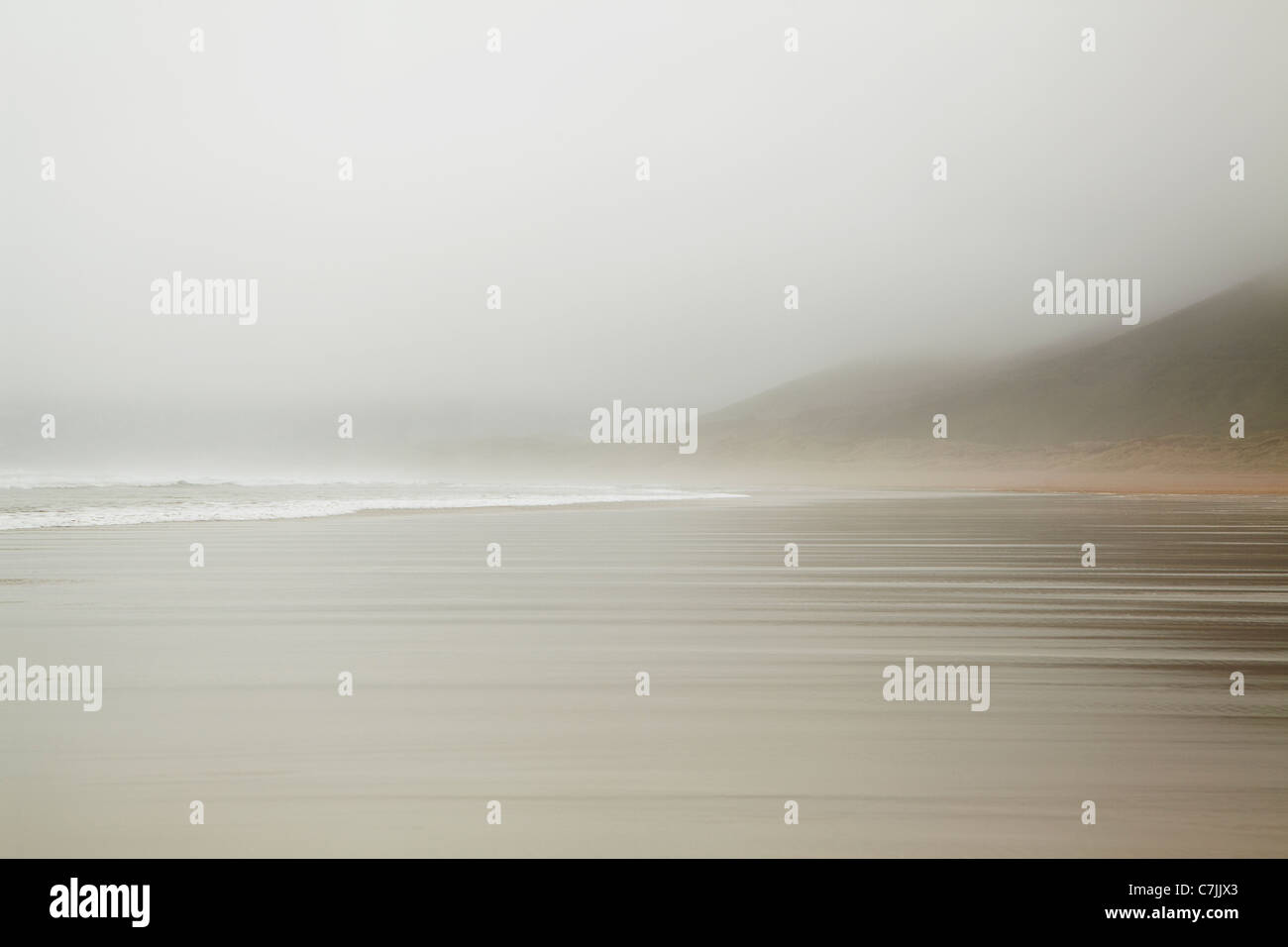 Waves washing up on foggy beach Stock Photo