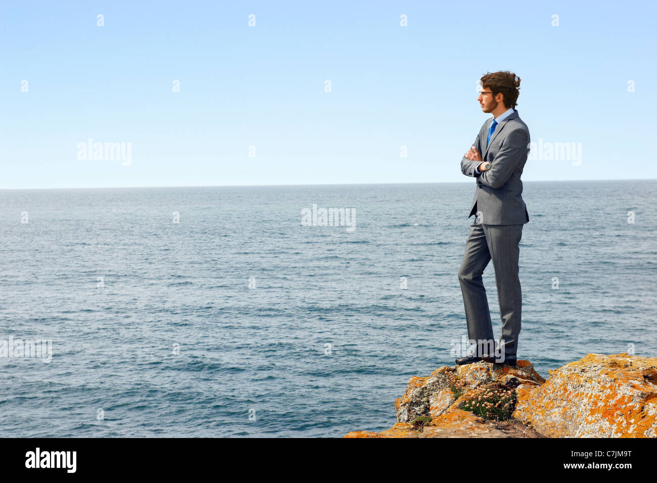 Businessmen standing on cliff edge Stock Photo