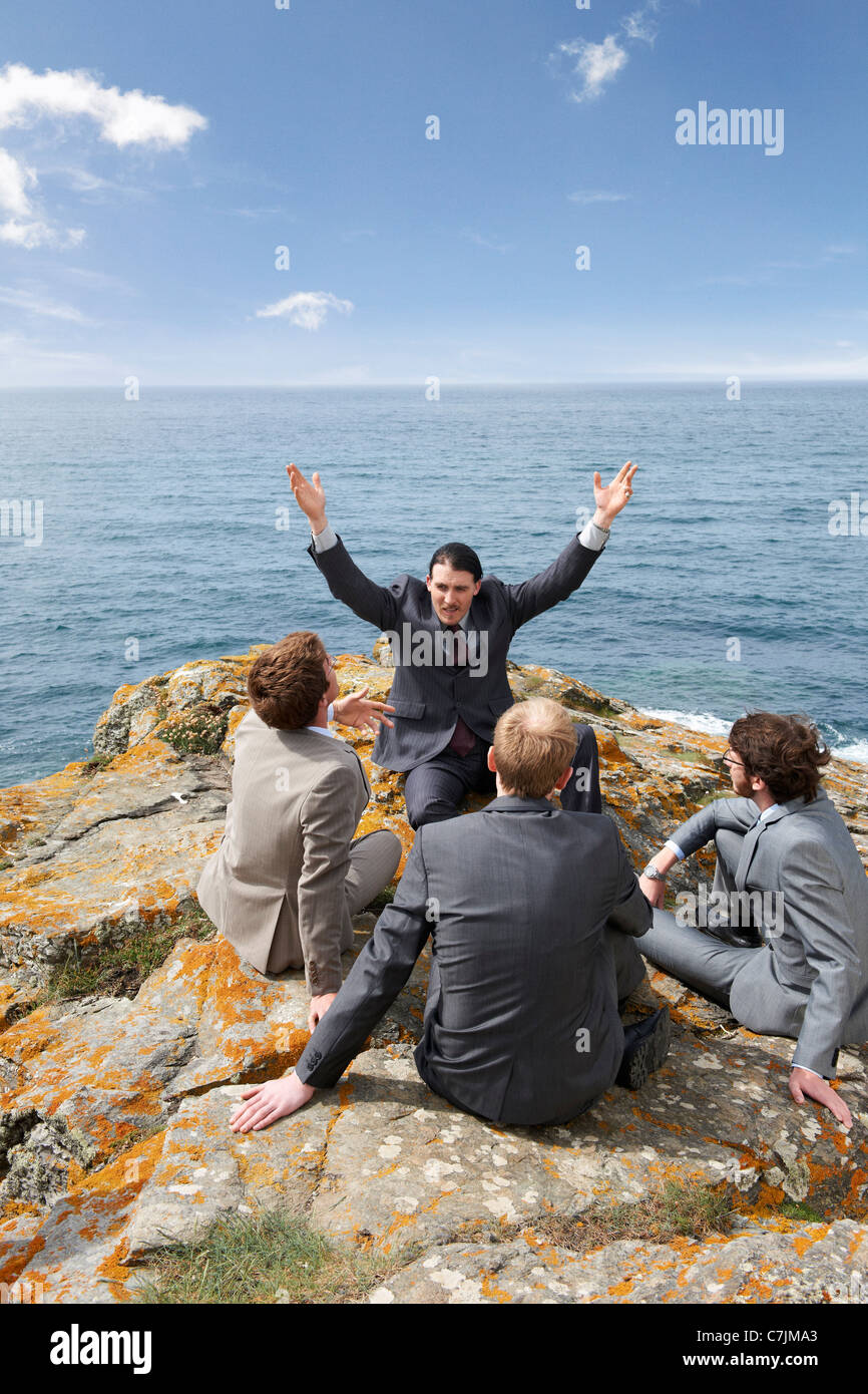 Businessmen talking on cliff Stock Photo