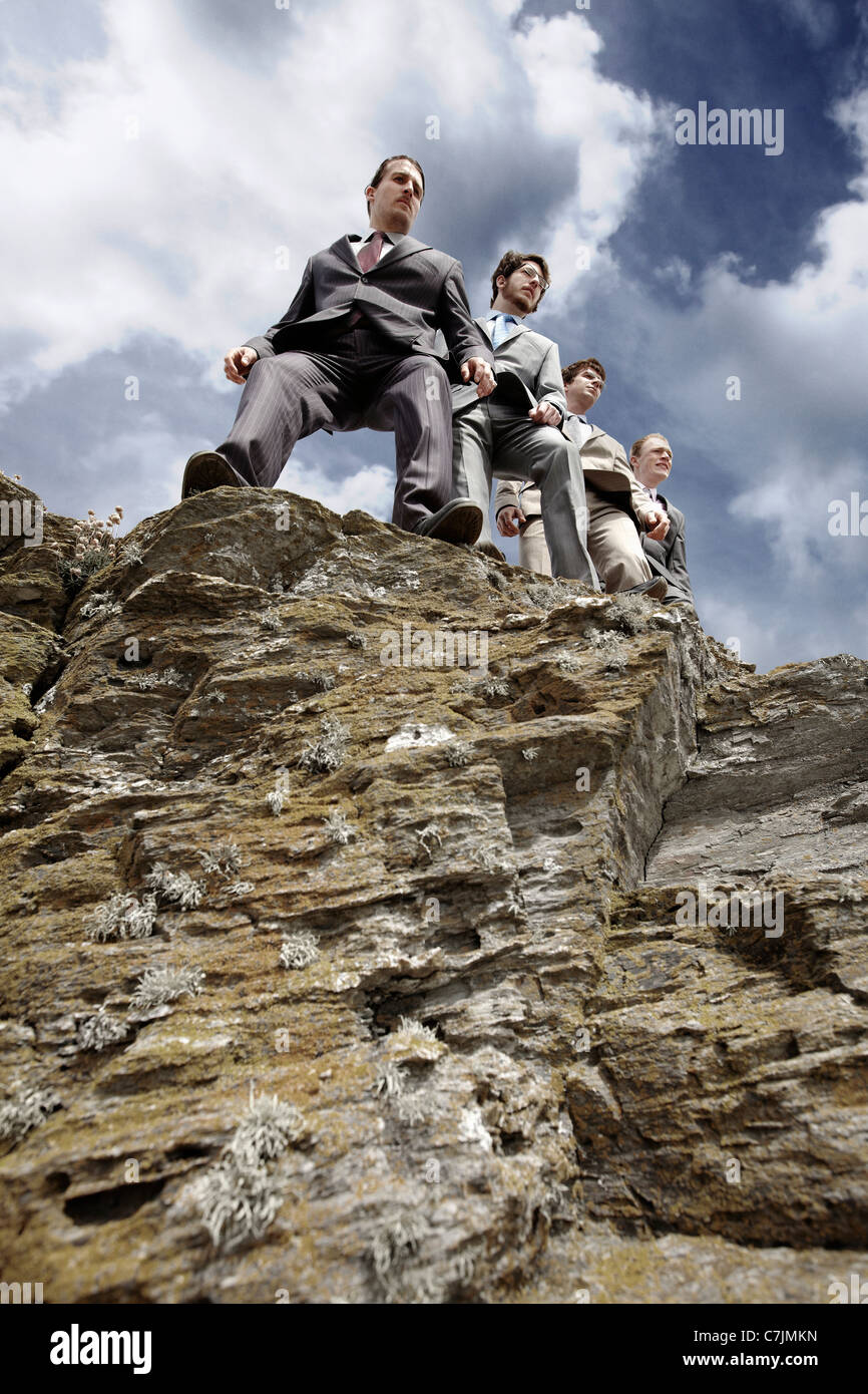 Businessmen peering over cliff edge Stock Photo