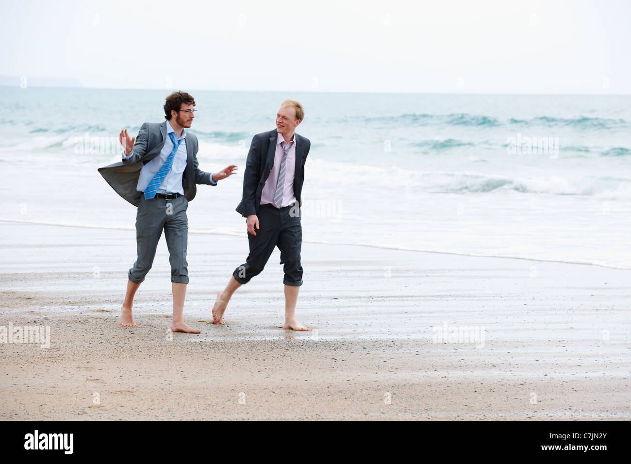 Businessmen walking on beach Stock Photo
