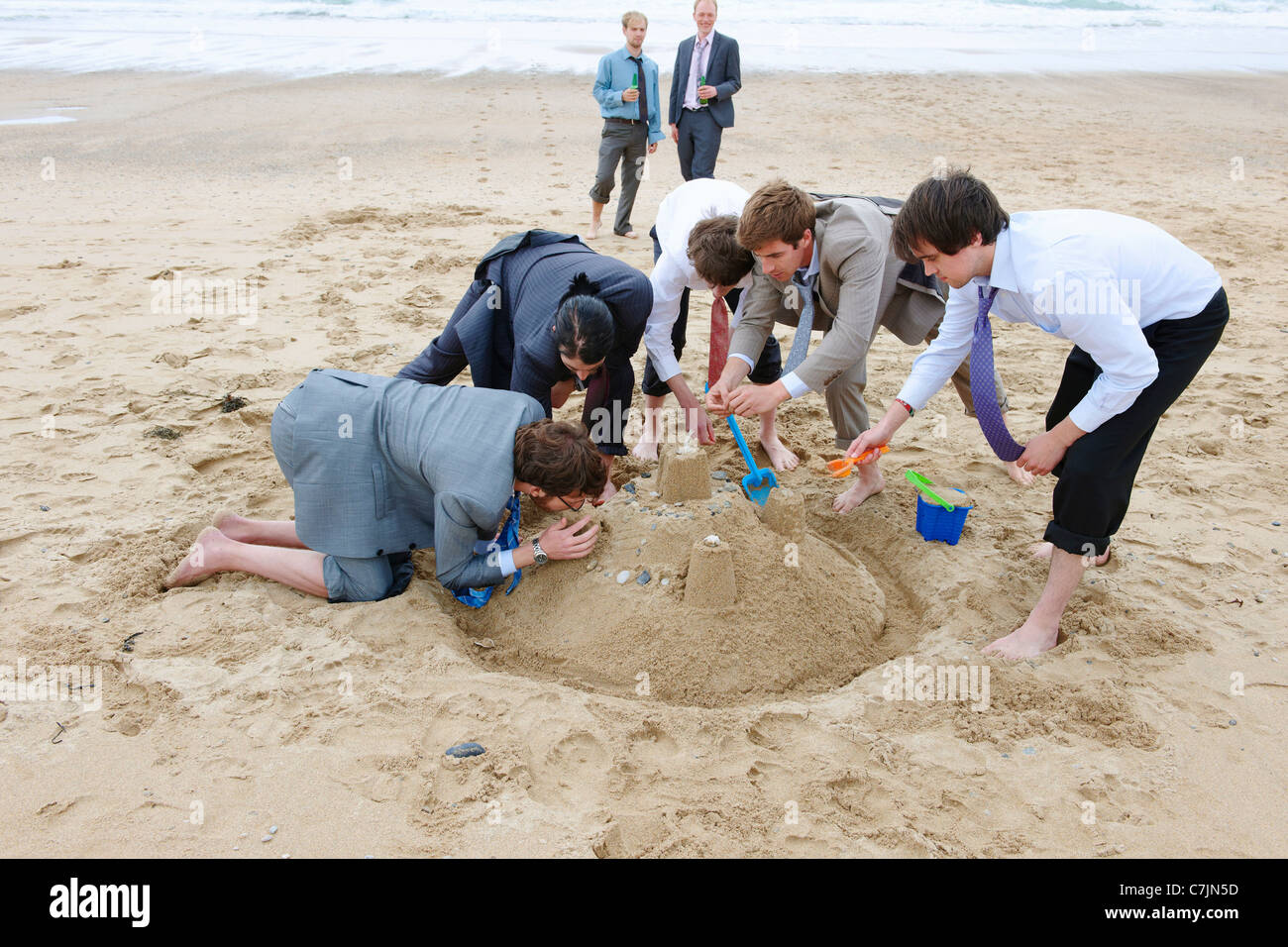 Businessmen building sand castle Stock Photo