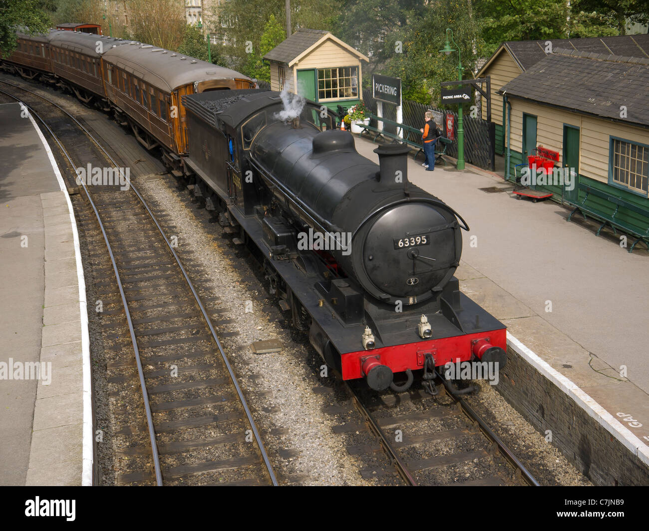 A train of ex LNER teak coaches arriving at the North Yorkshire Moors Railway Pickering station hauled by a Q6 class steam loco Stock Photo
