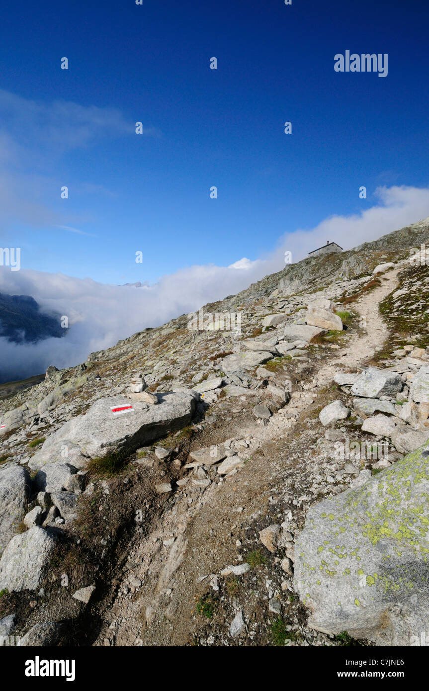 Switzerland. Signed hiking path above Lake Trübten leading uphill towards a small hut and further on to the Sidelhorn. Stock Photo