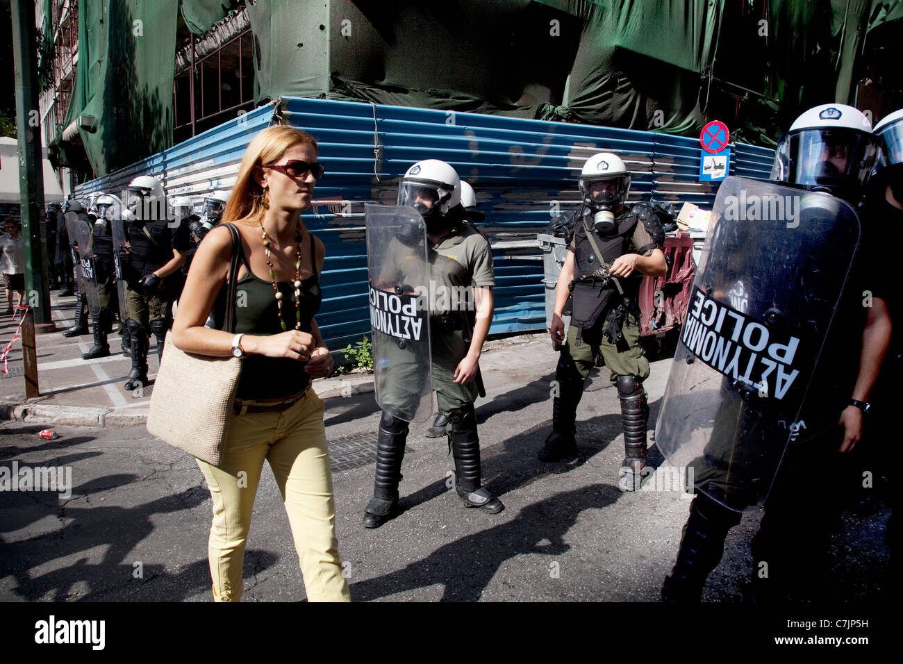 Woman passes riot police at student demonstration against austerity measures and planned education reforms in Athens, Greece. Stock Photo