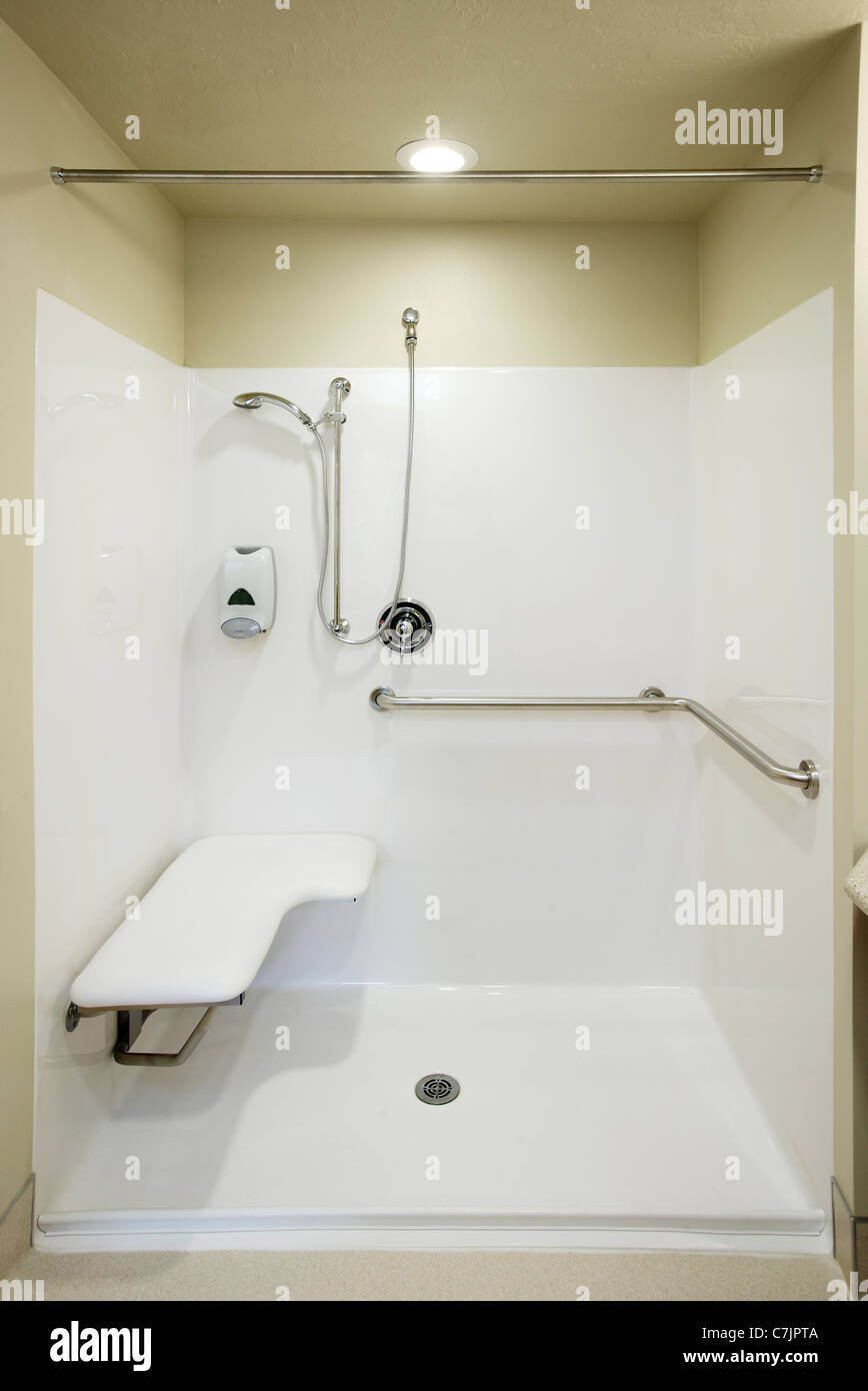 An image of the safety bars, seat and plumbing fixtures in a roll in shower stall Stock Photo