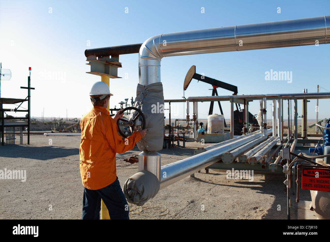 Worker adjusting pipes at oil field Stock Photo