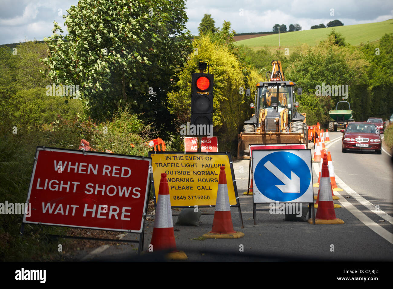 Waiting in car looking out of windscreen at red light traffic signals at roadworks and oncoming vehicles Stock Photo