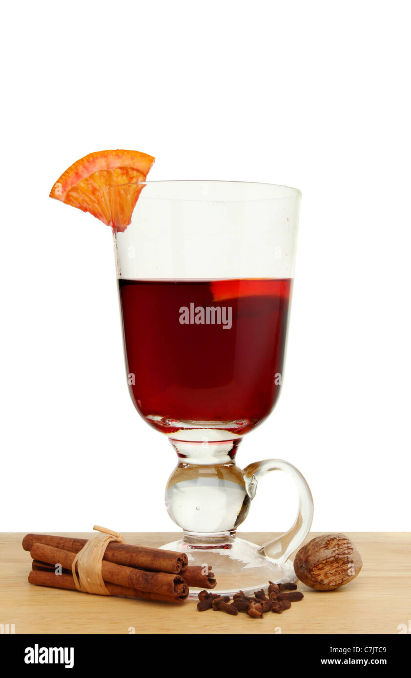Glass of mulled wine with a slice of orange and spices on a wooden surface against a white background Stock Photo