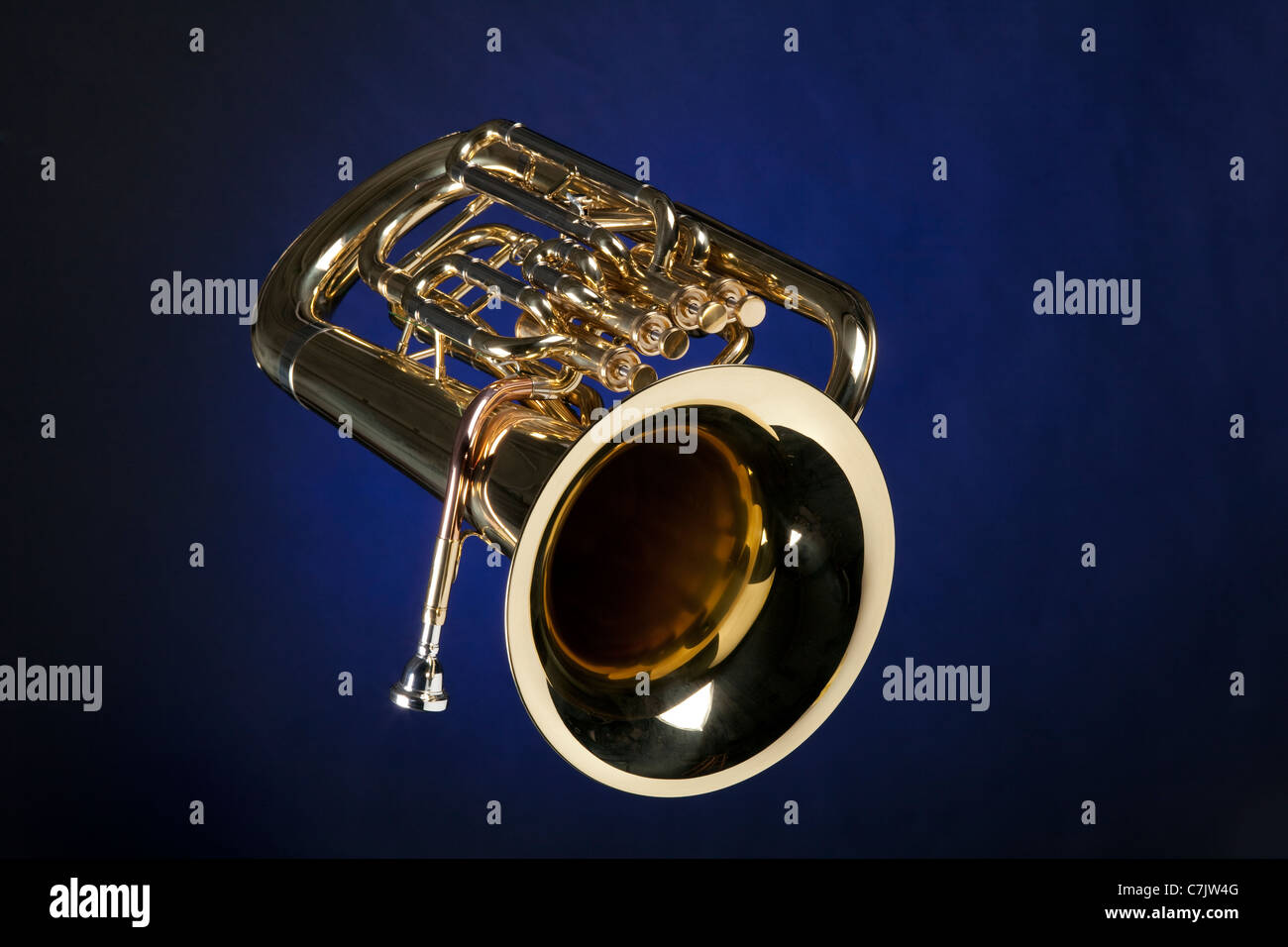 A gold brass euphonium tuba baritone horn isolated against a blue background. Stock Photo