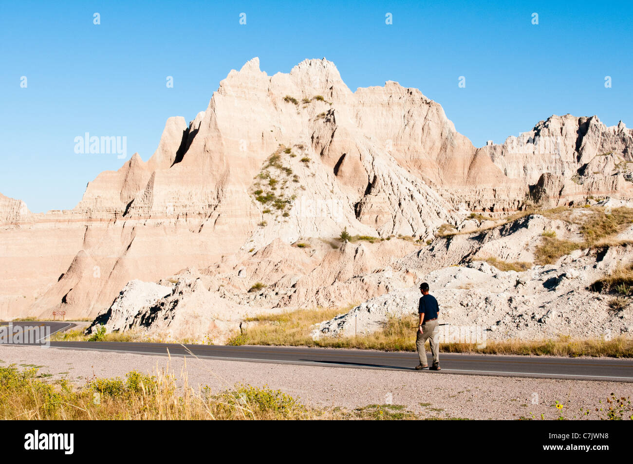 A hiker walks along the scenic Badlands Loop Road in Badlands National