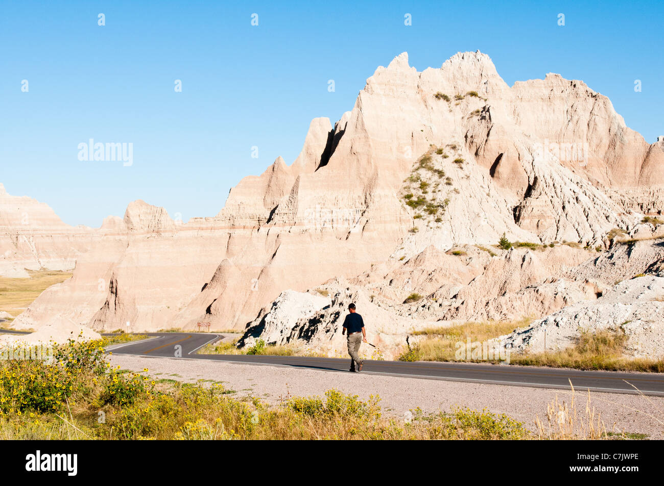 A hiker walks along the Badlands Loop Road in Badlands National Park in South Dakota Stock Photo