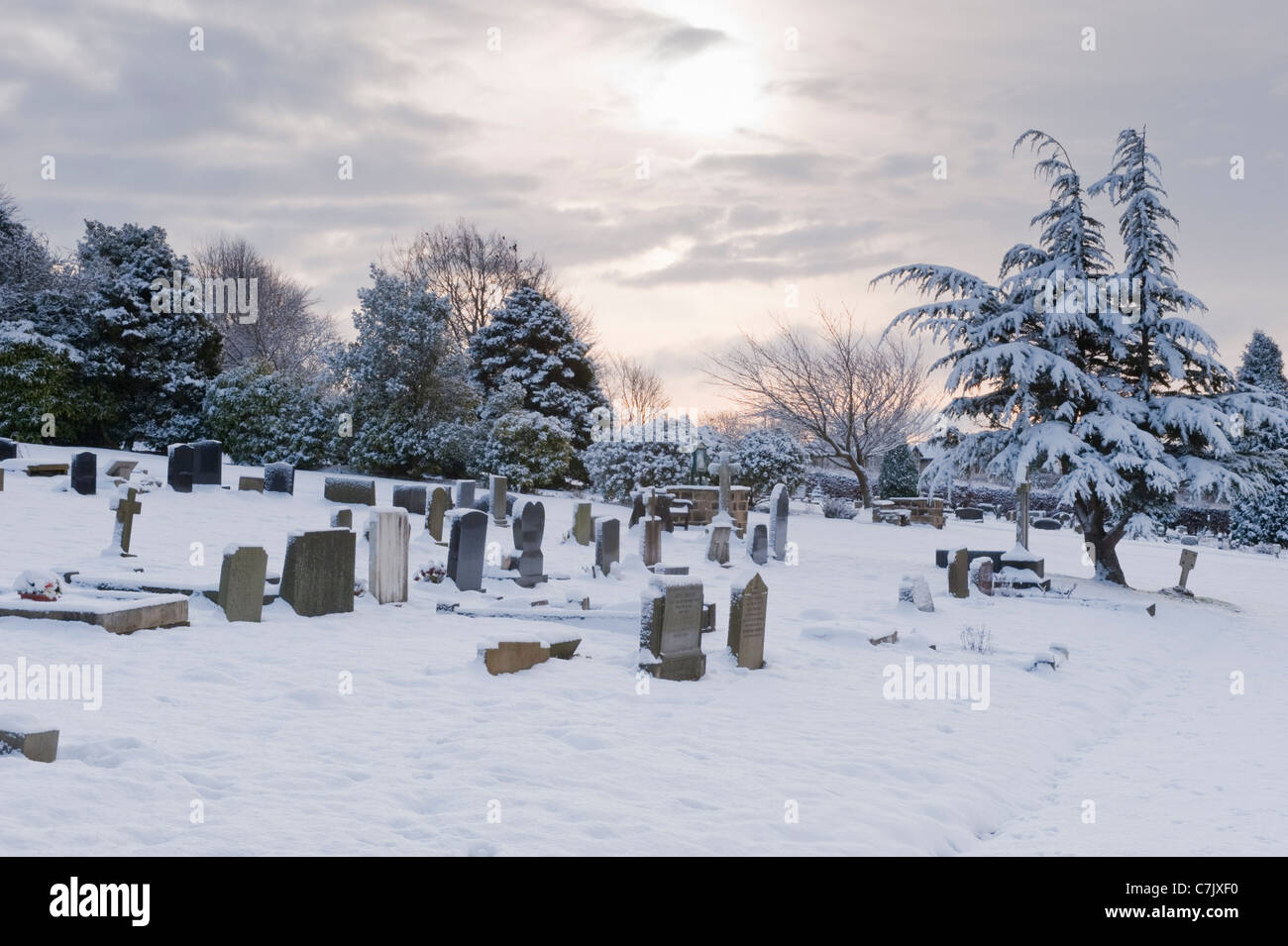 Snowy winter evening sunset graves & headstones in quiet, white, snow