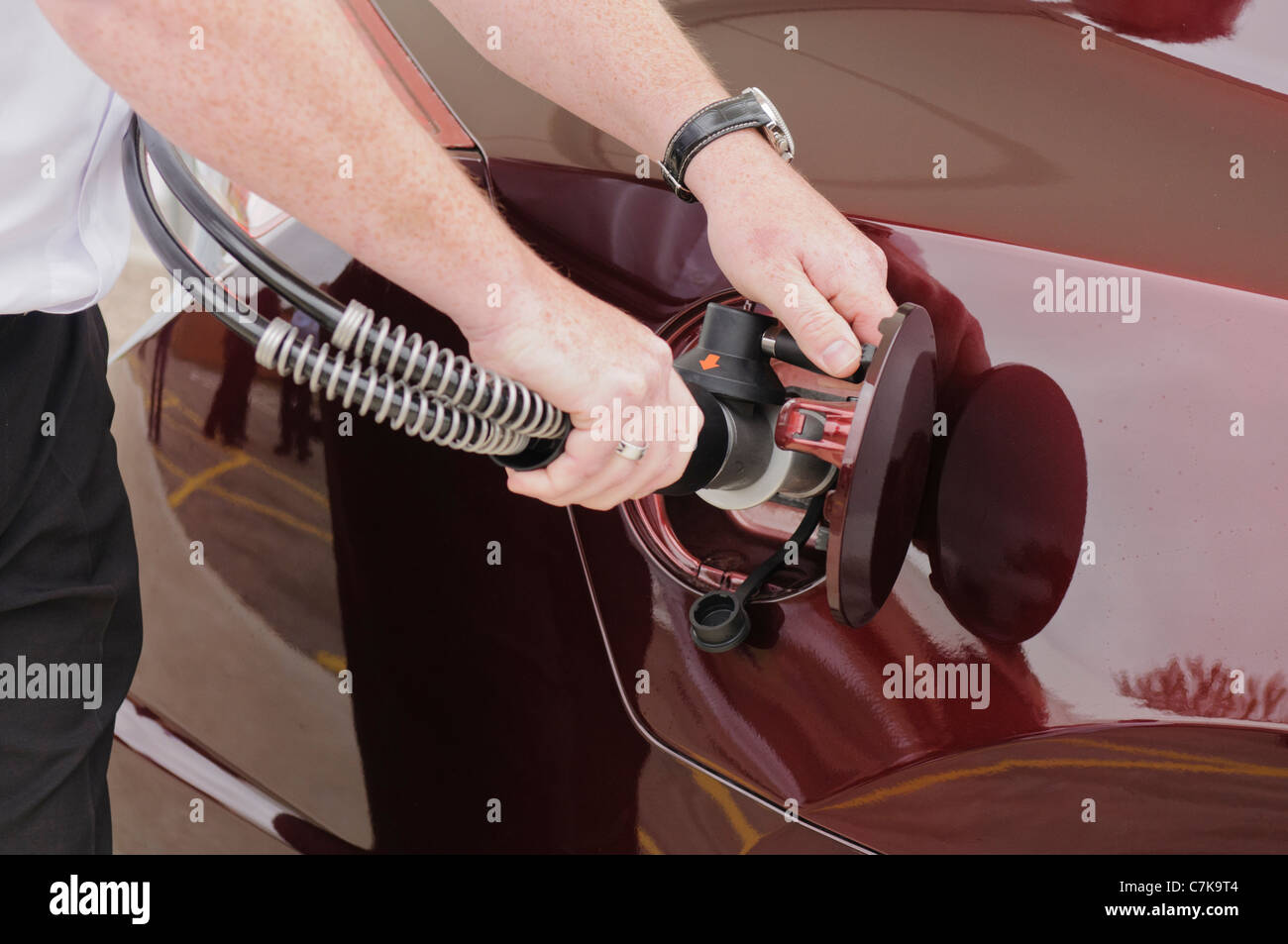 Man attaches nozzle to car while refuelling a hydrogen powered vehicle Stock Photo