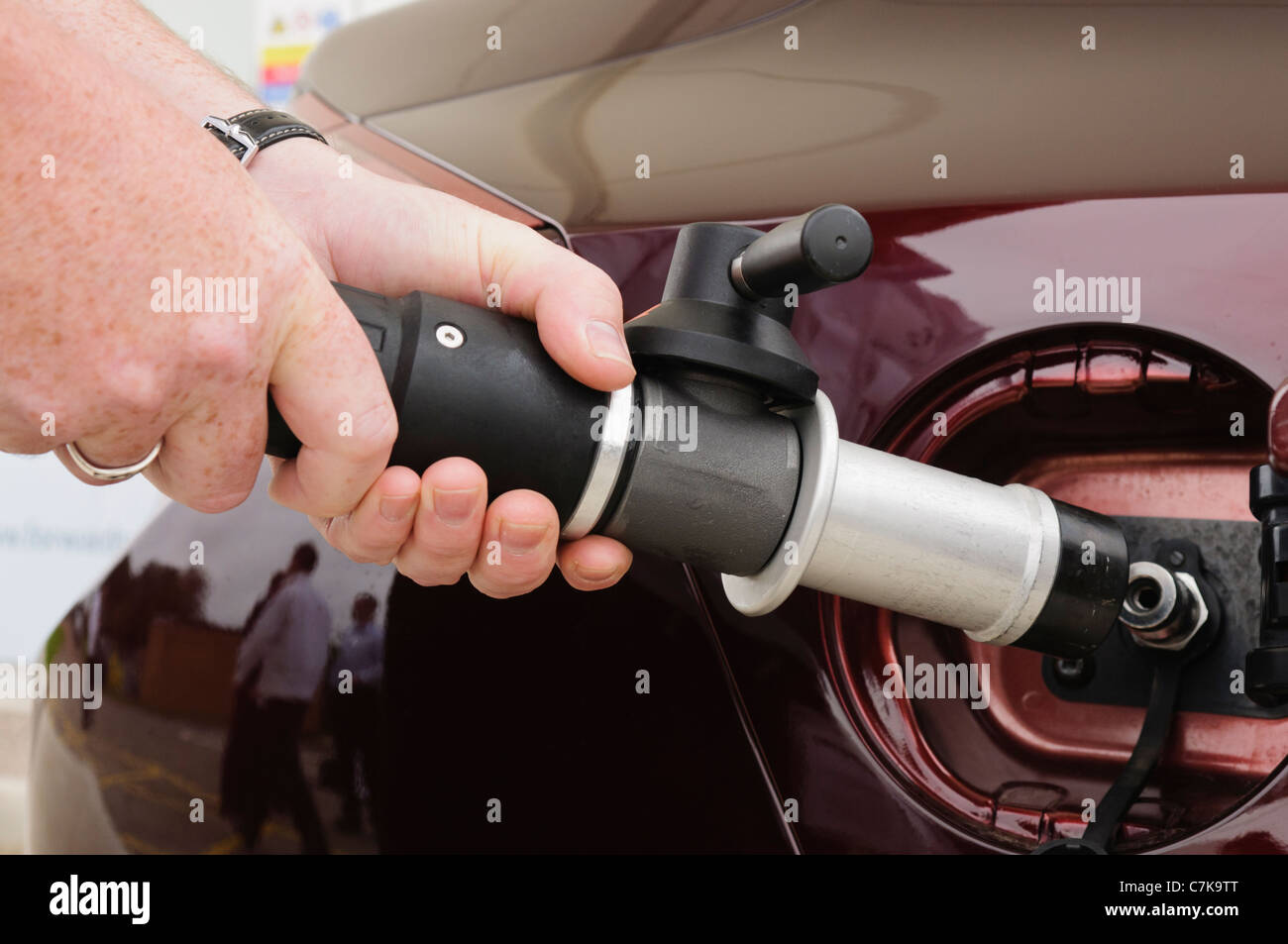 Man attaches nozzle to car while refuelling a hydrogen powered vehicle Stock Photo