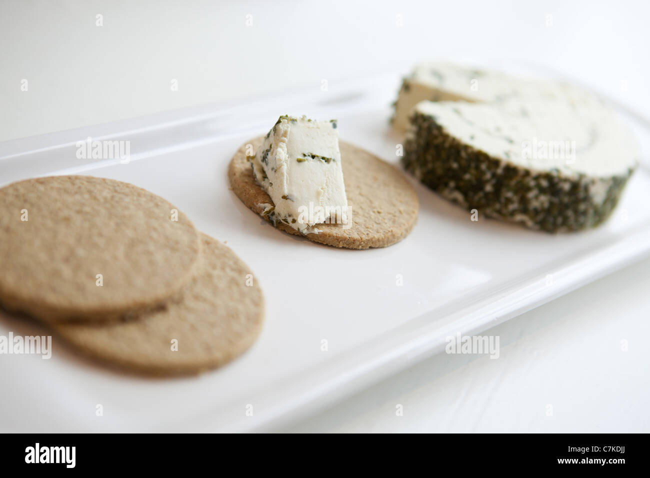 Three oatcakes on a plate with a block of garlic and herb cream cheese Stock Photo