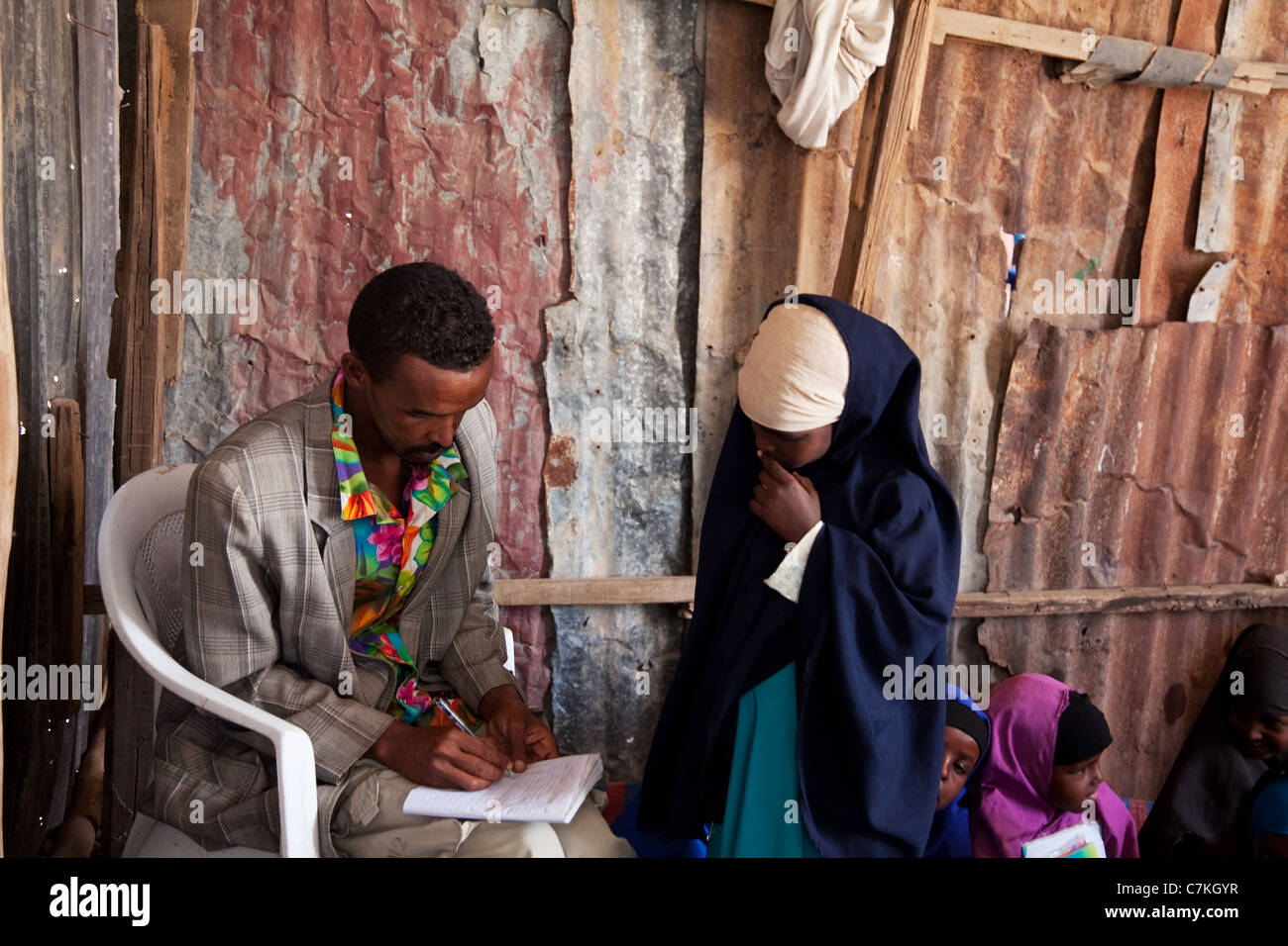 Teacher Faysal marks school work in a small school in Somaliland. Stock Photo