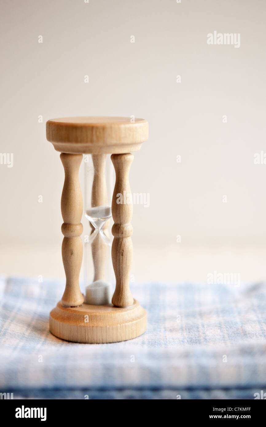 A wooden egg timer sitting on a blue checked tea towel Stock Photo
