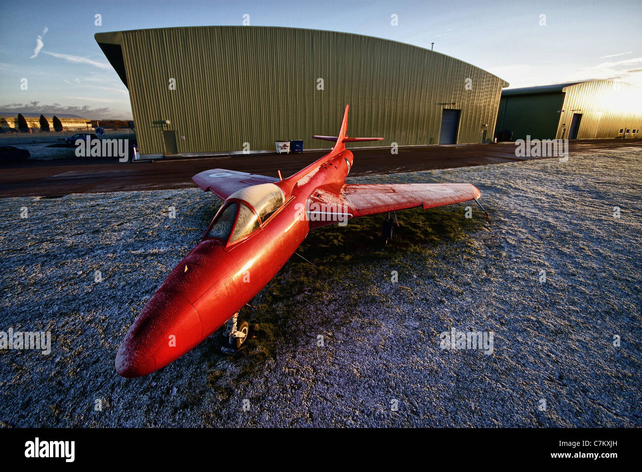 high shot of red Hawker Hunter jet fighter in front of hangars at Kemble airfield Stock Photo