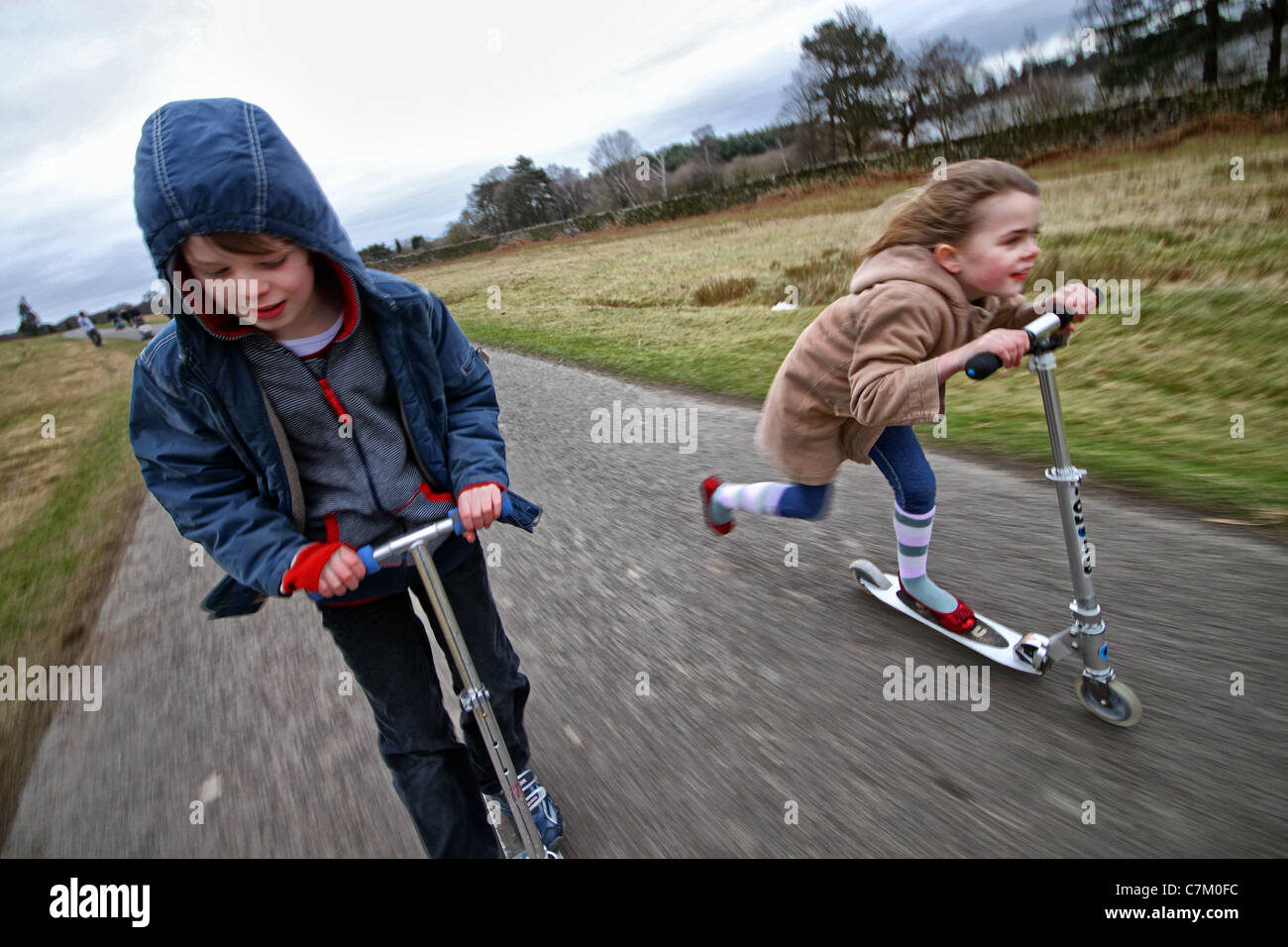 boy and a girl scootering in Bradgate Park Leicestershire Stock Photo