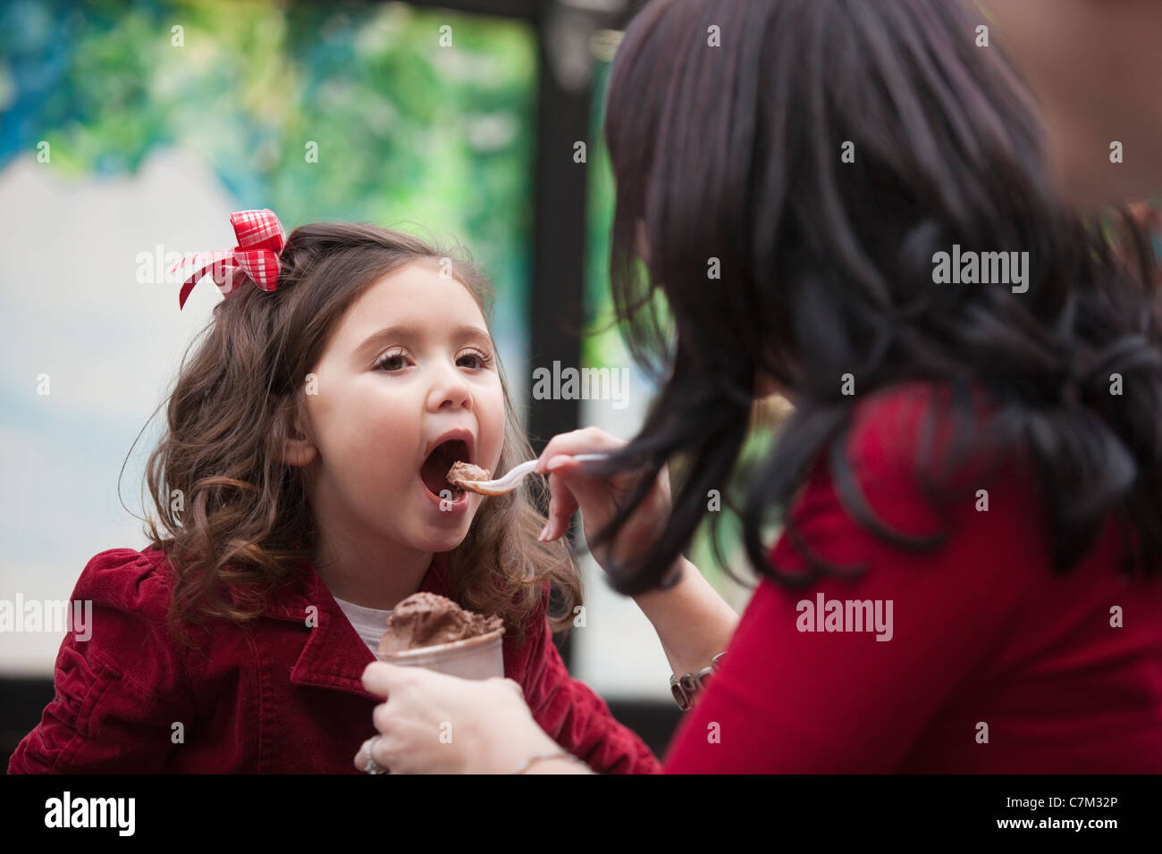 Woman feeding ice cream to her daughter Stock Photo