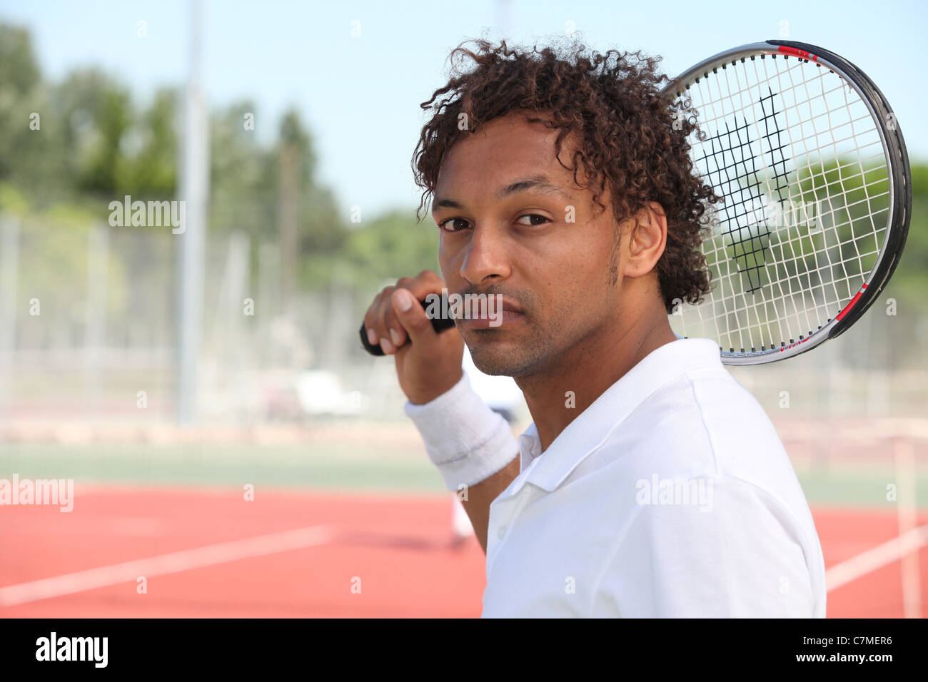 Male tennis player holding racquet over shoulder during game on hard