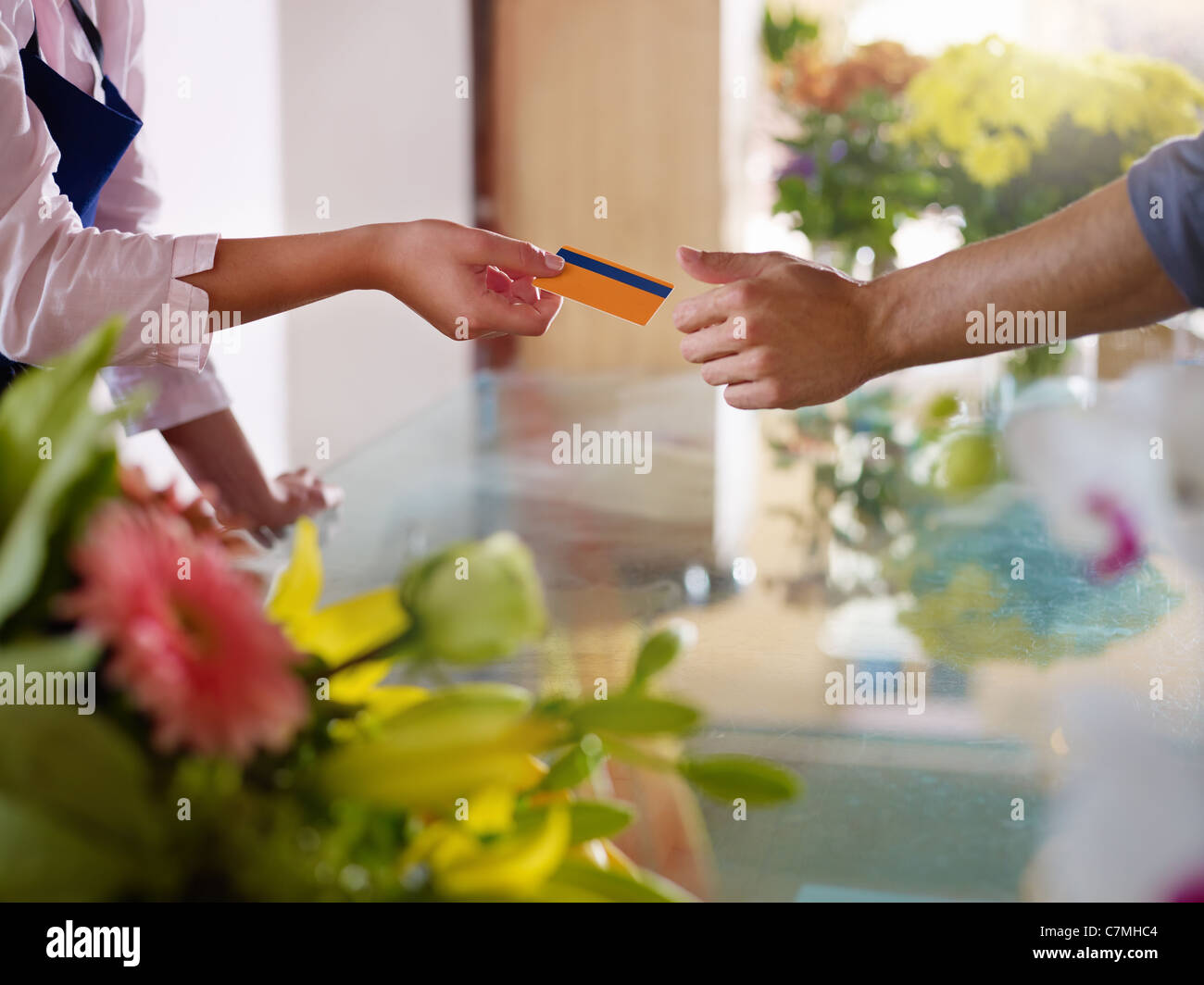 Young woman working as florist giving credit card to customer after purchase. Horizontal shape, closeup Stock Photo