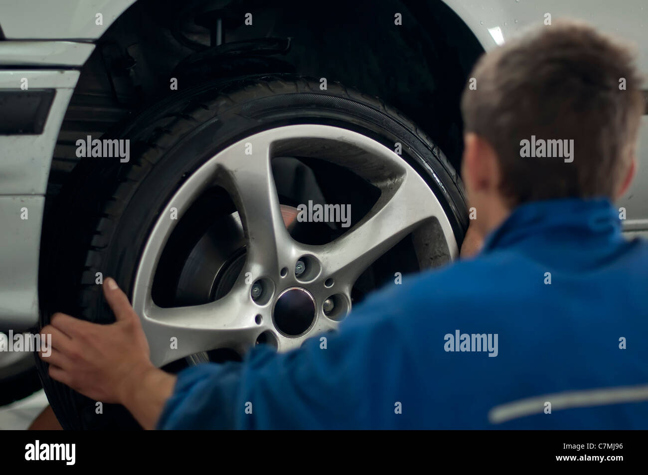 Mechanic put a car tire with alloy wheel Stock Photo Alamy