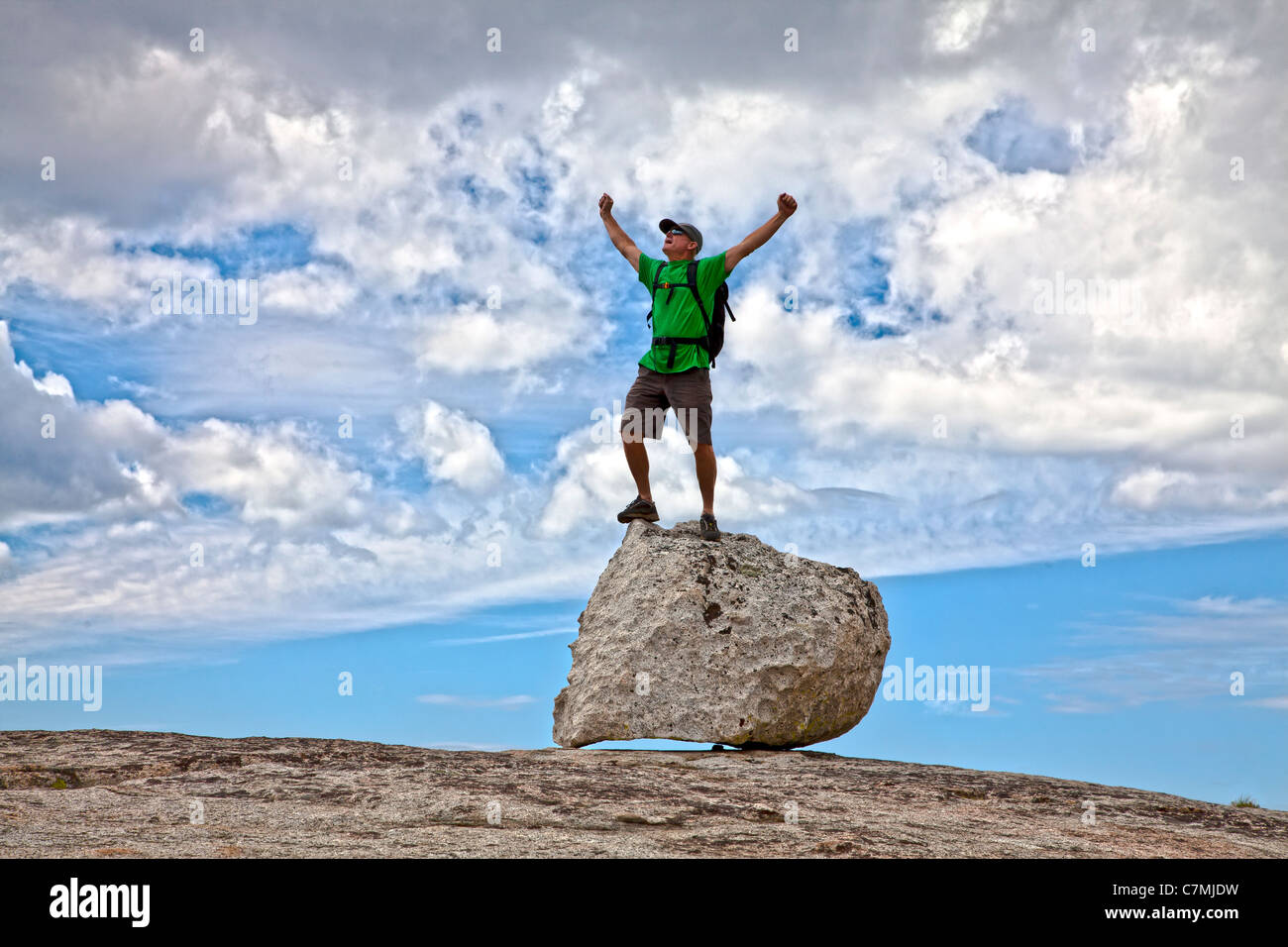 Male rock climber celebrates on the summit after a successful ascent. Stock Photo