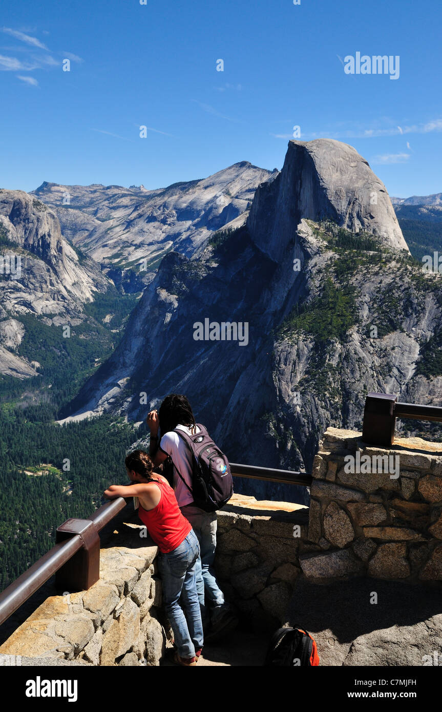 A young couple stand enjoying the view from Glacier Point. Yosemite National Park, California, USA. Stock Photo