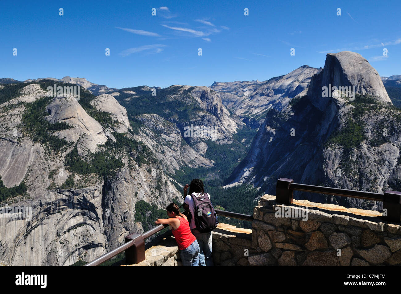 A young couple stand enjoying the view from Glacier Point. Yosemite National Park, California, USA. Stock Photo