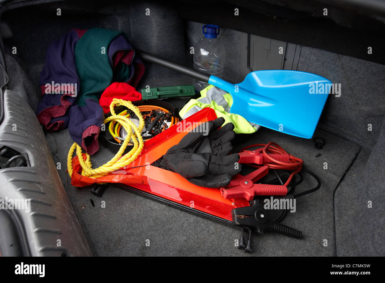 winter emergency equipment in the boot of a car including snow shovel snow chains tow rope spare clothes hi vis vest jump leads Stock Photo