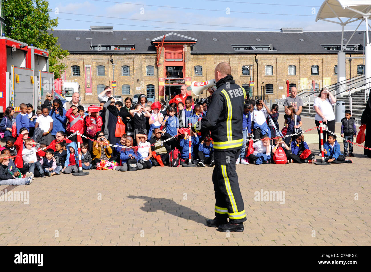 Fireman explaining fire hazards to school children on educational visit to National UK Rescue Organisations challenge event at Excel Centre London UK Stock Photo