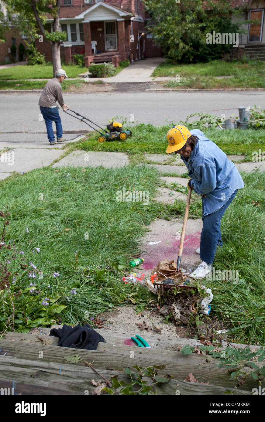 Detroit, Michigan - Members of the Three Mile Drive block club clean trash and weeds from a vacant home in their neighborhood. Stock Photo