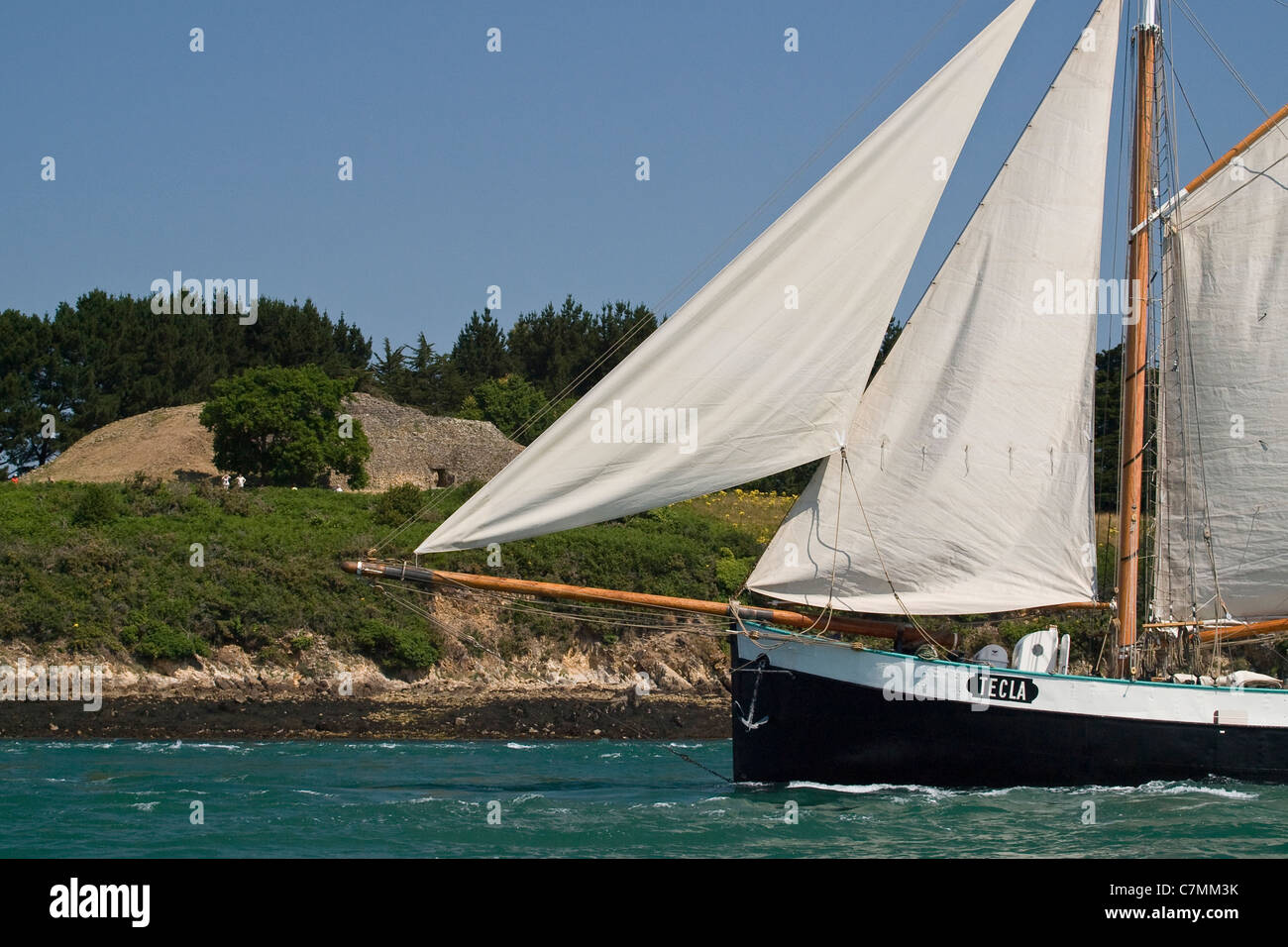 Tall ship Tecla sailing in front of a prehistoric mound. Bay of Morbihan, Brittany, France, Europe. Stock Photo
