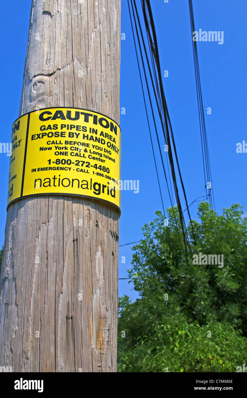 National grid caution sign on wooden electrical power pole on New York city borough street, USA Stock Photo