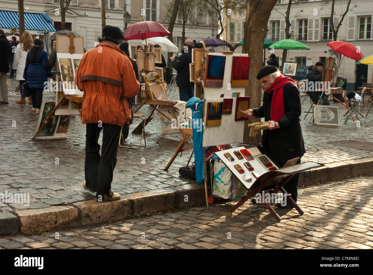 Atmospheric and colorful autumn street scene. Local artist setting up stall to sell paintings, with colorful umbrellas Stock Photo