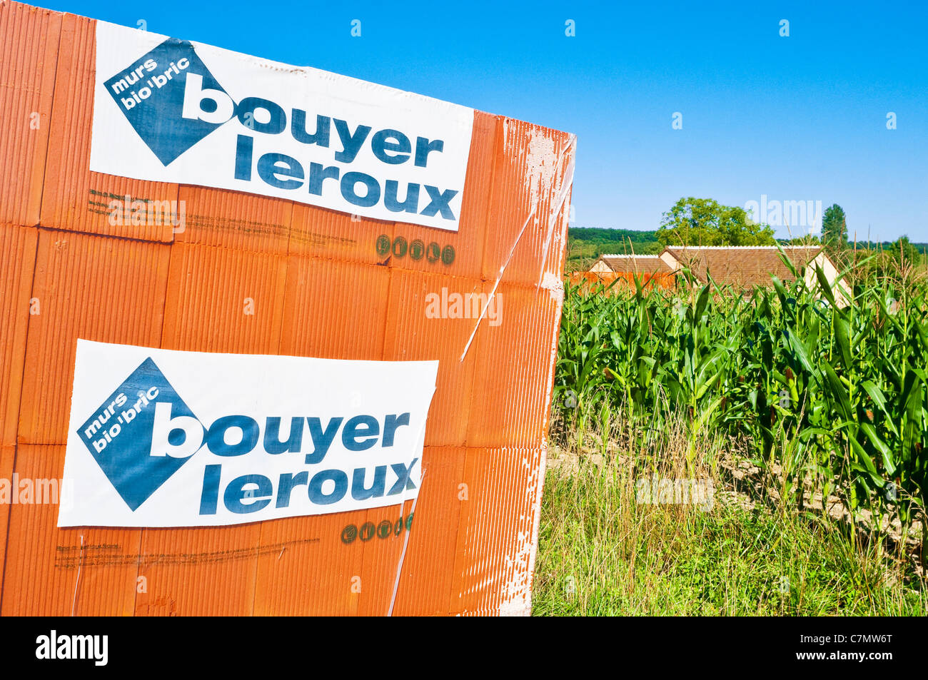 Stack of Bouyer Leroux bio-bricks next to farmland field of Maize - France. Stock Photo