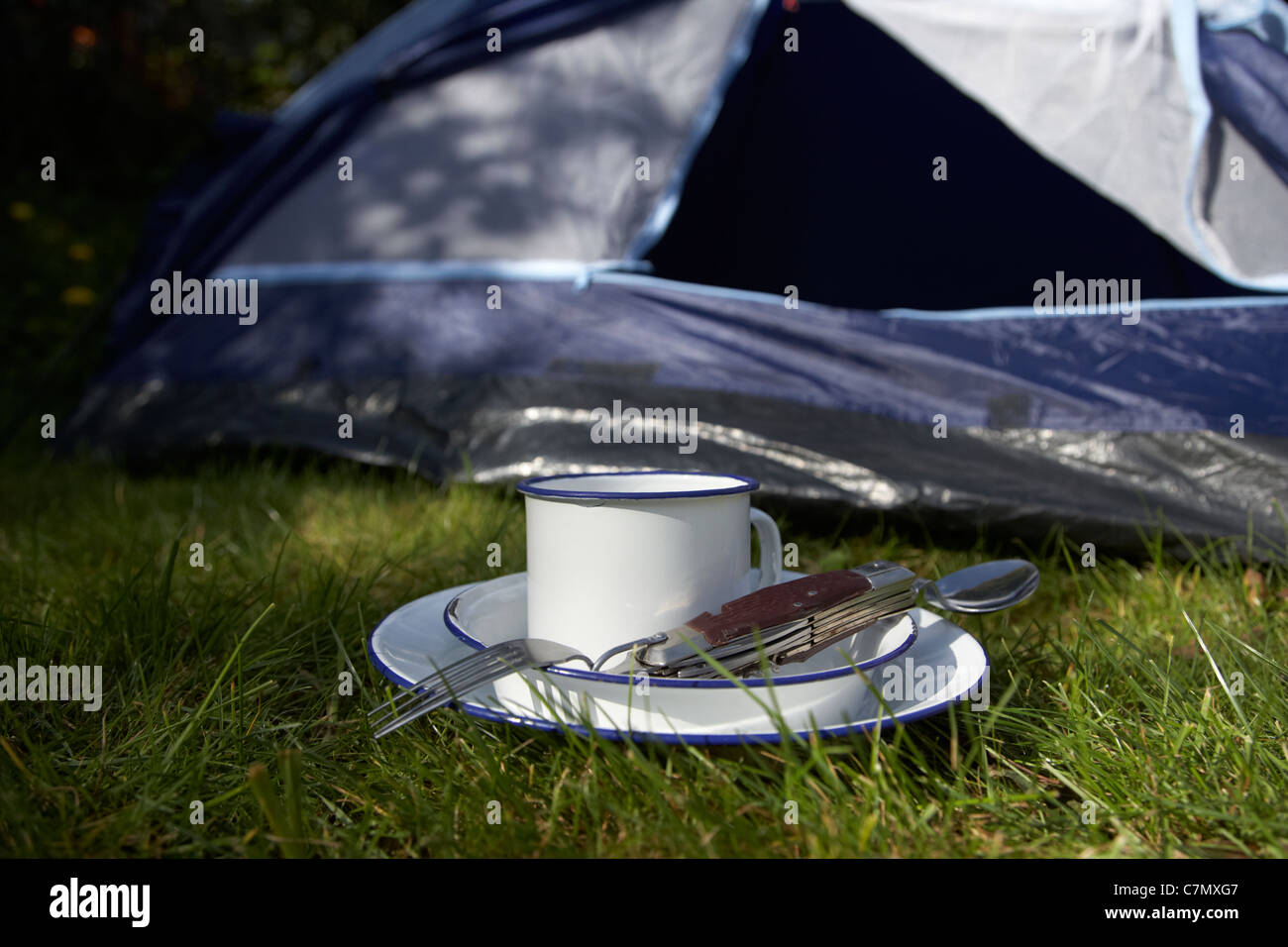tin plate cup and camping tool utensils in front of the open door of a